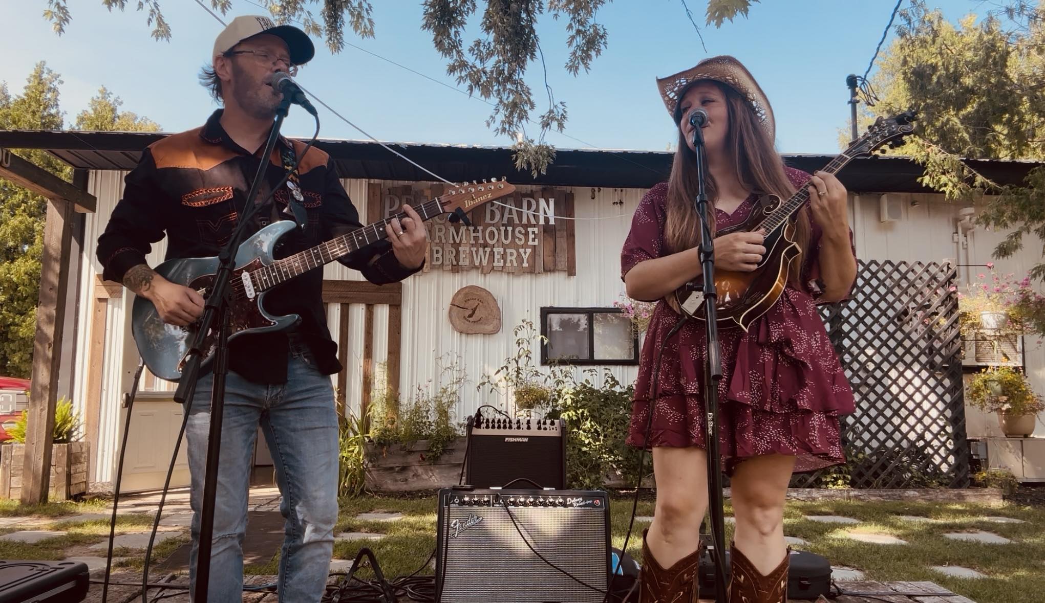 A man plays guitar and sings while a woman plays mandolin and sings.